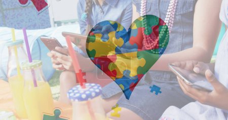 Téléchargez les photos : Image de pièces de puzzle colorées coeur sur les amis chantent smartphone et tablette. autisme, difficultés d'apprentissage, concept de soutien et de sensibilisation image générée numériquement. - en image libre de droit