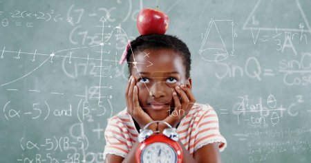 Foto de Imagen de fórmulas matemáticas sobre la niña afroamericana reflexiva con manzana sobre pizarra. aprendizaje, educación y concepto escolar imagen generada digitalmente. - Imagen libre de derechos