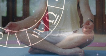 Photo for Image of horoscope zodiac wheel over caucasian man practicing yoga. Star signs, horoscope and yoga meditation concept digitally generated image. - Royalty Free Image