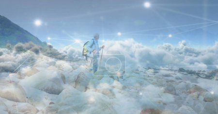 Photo for Caucasian senior man hiking in countryside, over fast moving clouds and network of connections. active outdoor lifestyle, healthy retirement and global communication concept, digitally generated image. - Royalty Free Image