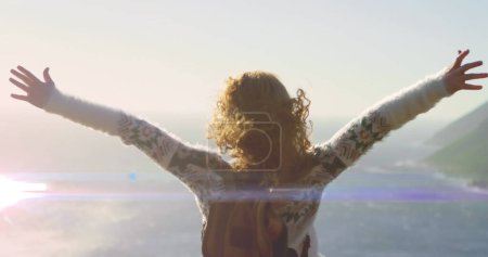 Téléchargez les photos : Image de sentiers lumineux sur une femme caucasienne avec les bras tendus sur la plage. ne jamais abandonner le concept de jour et de célébration, image générée numériquement. - en image libre de droit