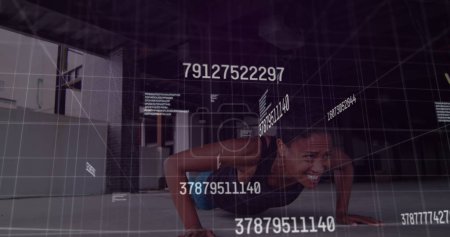 Foto de Imagen de números cambiantes sobre la mujer afroamericana en forma que preforma el ejercicio push up. Concepto de tecnología deportiva y fitness, - Imagen libre de derechos