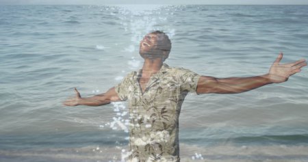 Foto de Imagen del mar sobre el hombre afroamericano con los brazos extendidos. nunca renunciar al concepto de día y celebración, imagen generada digitalmente. - Imagen libre de derechos