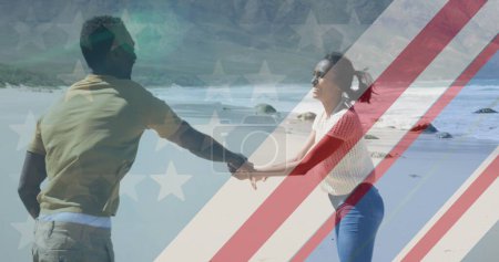 Téléchargez les photos : Image du drapeau américain sur un couple afro-américain dansant sur la plage. patriotisme et concept de célébration, image générée numériquement. - en image libre de droit