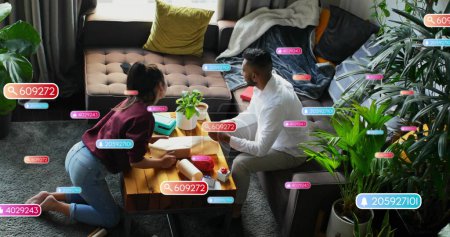 Image of social media notifications over diverse couple wrapping presents. Celebration, domestic life, social network, digital interface, internet and communication, digitally generated image.