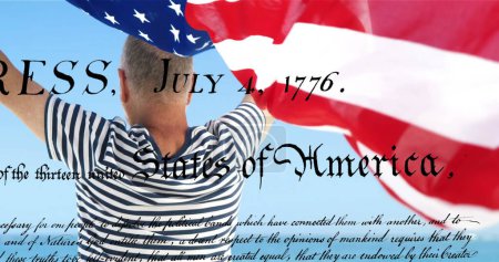 Digitales Bild einer geschriebenen Verfassung der Vereinigten Staaten, die sich auf dem Bildschirm bewegt, während im Hintergrund ein kaukasischer Mann eine amerikanische Flagge hochhält