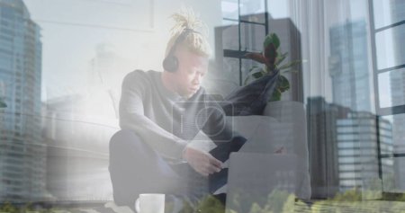 Téléchargez les photos : Image d'icônes statistiques flottant sur un homme afro-américain albinos travaillant sur un ordinateur portable à la maison. bureau à domicile et concept d'entreprise, image générée numériquement. - en image libre de droit