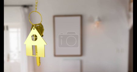 Téléchargez les photos : Porte-clés doré en forme de maison accroché au foyer, avec fond flou. Symboliser l'accession à la propriété, accroché sur fond d'intérieur - en image libre de droit