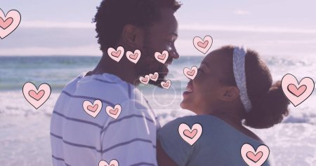 Image of heart icons over african american couple on beach. fashion and lifestyle concept digitally generated image.