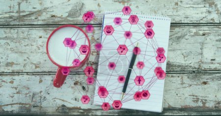A close-up of a coffee cup, notepad, and pen on a wooden plank, with an image of a network of connections with pink glowing digital icons forming a globe rotating on a black background. Background with abstract texture and design concept.