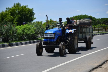 Foto de Viluppuram, India: 28 de agosto de 2022: El joven que conduce el tractor y tira de la carga en la carretera nacional india Travel. Vehículo tractor indio en las carreteras indias, vehículo en la carretera india . - Imagen libre de derechos