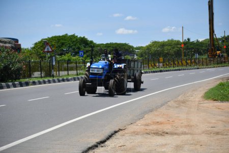 Photo for Viluppuram, India: August 28th 2022: The Young Man Driving Tractor and Pulling Load on Indian National Highway Road Travel. Indian Tractor vehicle on Indian Road Highways, Vehicle on Indian Road . - Royalty Free Image