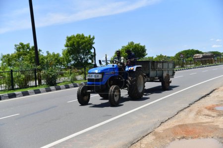 Foto de Viluppuram, India: 28 de agosto de 2022: El joven que conduce el tractor y tira de la carga en la carretera nacional india Travel. Vehículo tractor indio en las carreteras indias, vehículo en la carretera india . - Imagen libre de derechos