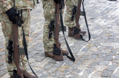 The legs of a Lithuanian camouflage soldier and his rifle