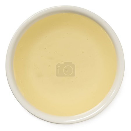 Rice syrup in a white ceramic bowl isolated on white. Top view.