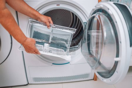Linges de nettoyage femme au foyer et la saleté du filtre sèche-linge. Filtre à peluches de séchoir à vêtements recouvert de peluches. Enlever la peluche du filtre à air sale de la machine à sécher avant utilisation de la machine.
