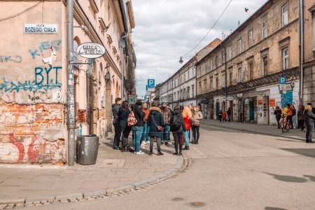 Téléchargez les photos : Cracovie, Pologne - 17 août 2022 : Groupe de touristes réunis sur la vieille ville de Cracovie, une place publique et l'un des endroits les plus connus et les plus fréquentés de la ville, pour une visite guidée gratuite. - en image libre de droit