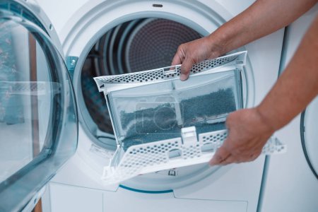Linges de nettoyage femme au foyer et la saleté du filtre sèche-linge. Filtre à peluches de séchoir à vêtements recouvert de peluches. Enlever la peluche du filtre à air sale de la machine à sécher avant utilisation de la machine.