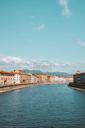 Téléchargez les photos : Belle vue sur les bâtiments le long de la rivière Arno à Pise, Italie. Un pont passe au-dessus de la rivière et les maisons des deux côtés donnent sur l'eau. Photo de haute qualité - en image libre de droit