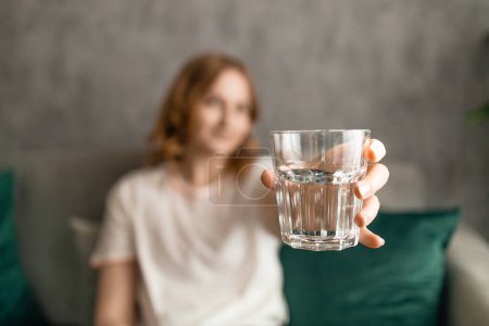 Foto de Mujer bonita sonriente sostiene un vaso de agua en casa - Imagen libre de derechos