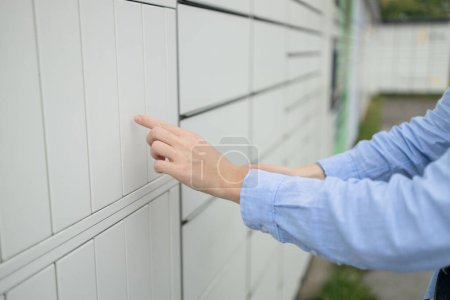 Photo for Beautiful woman picking up a package from a smart electronic steel parcel locker box, automatic mailboxes. Pachkomat delivery service, collection machine - Royalty Free Image