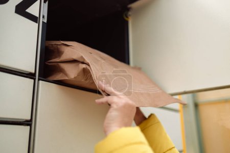 Woman putting box to automated parcel machine.