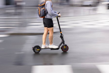 Téléchargez les photos : Motion blur picture of an unrecognizable person with an electric scooter on a city street - en image libre de droit