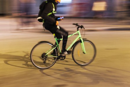 Photo for Picture with intentional motion blur effect of a bicycle rider on a city street at night - Royalty Free Image