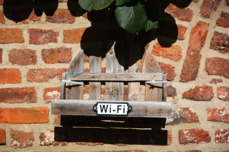 Photo for Wifi sign at a weathered wooden box on an old brick wall - Royalty Free Image