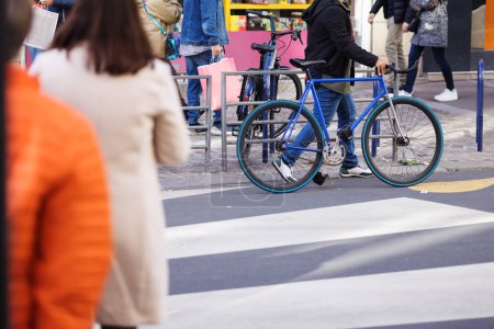 Photo for Street scene in the city with street crossing pedestrians and a person who pushes a bicycle - Royalty Free Image