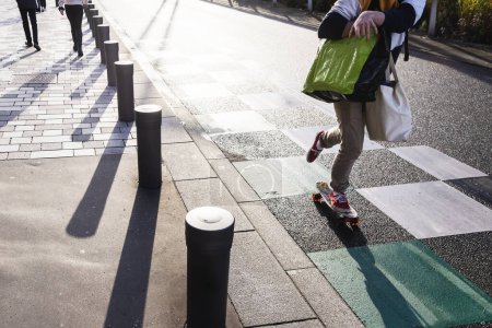 Téléchargez les photos : Young person with shopping bags on a skateboard on the move on a city street - en image libre de droit