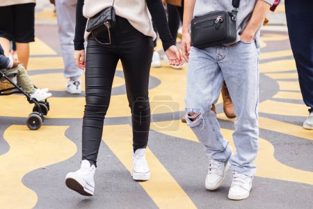 Photo for Young couple walks between a crowd of people on a city street - Royalty Free Image