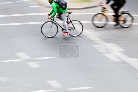 Téléchargez les photos : Image dans la caméra fait flou de mouvement des cyclistes traversant une intersection - en image libre de droit