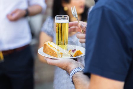 Photo for Man with a plate of cake and a glass of beer at a celebration - Royalty Free Image