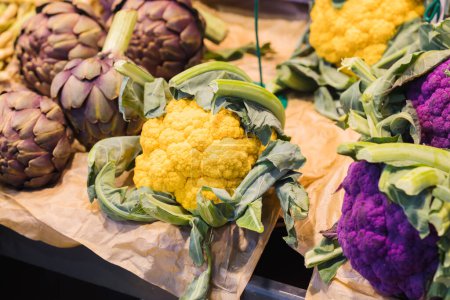 Foto de Coliflores de diferentes colores y alcachofas en un puesto de mercado de un mercado de agricultores - Imagen libre de derechos