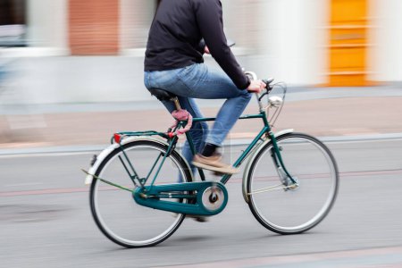Téléchargez les photos : Homme méconnaissable avec un téléphone dans la main monte un vélo sur une rue de la ville - en image libre de droit