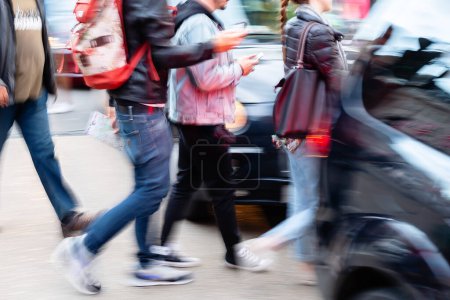 Téléchargez les photos : Image with motion blur of people crossing a city street between the cars - en image libre de droit