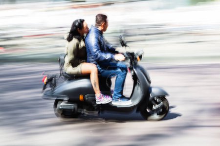 Photo for Picture in intentional motion blur of a couple on a scooter driving in the city - Royalty Free Image