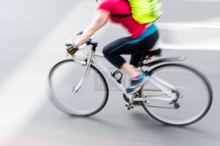 Téléchargez les photos : Picture with camera made motion blur effect of a sporty cyclist with a racing bike on the road - en image libre de droit