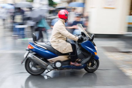Téléchargez les photos : Image en flou de mouvement intentionnel d'un homme avec un scooter conduisant dans la ville - en image libre de droit