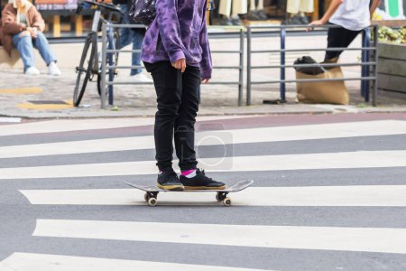 Téléchargez les photos : Photo d'une jeune personne méconnaissable avec un skateboard dans une rue de la ville - en image libre de droit