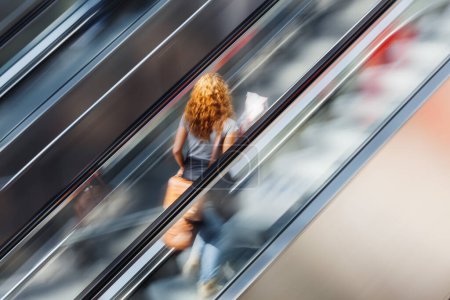 Photo for Picture of a woman on an escalator with motion blur effect - Royalty Free Image