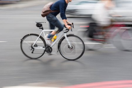 Téléchargez les photos : Image avec flou de mouvement intentionnel effet d'un homme sur un vélo de course dans la circulation de la ville - en image libre de droit