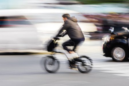 Photo for Picture of an abstract blurred picture of a bicycle rider in city traffic - Royalty Free Image