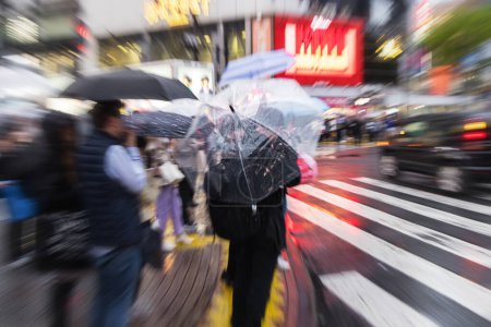 Foto de Imagen con efecto zoom de una multitud de personas con paraguas cruzando el cruce Shibuya en Tokio, Japón, en un día lluvioso - Imagen libre de derechos