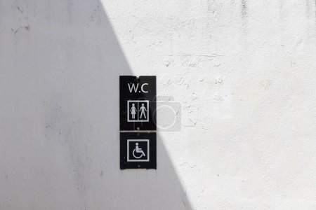 Foto de Imagen de un letrero para un inodoro, para mujeres y hombres y discapacitados, en una pared de la casa - Imagen libre de derechos