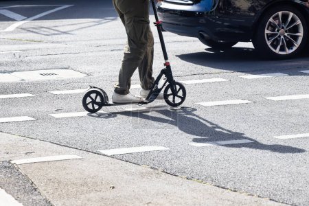 Téléchargez les photos : Personne avec un scooter de coup de pied sur la route dans la circulation de la ville - en image libre de droit