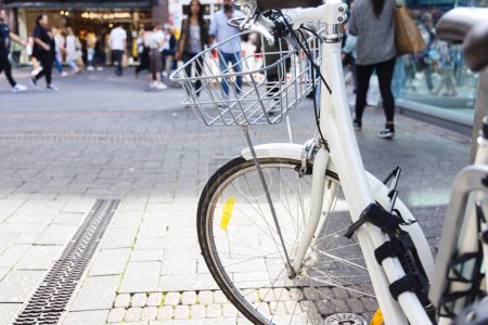Foto de Bicicleta con cesta de la compra con una zona peatonal borrosa y concurrida de una ciudad en el fondo - Imagen libre de derechos