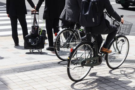 Téléchargez les photos : Photo d'hommes d'affaires japonais à vélo sur le trottoir de Tokyo - en image libre de droit