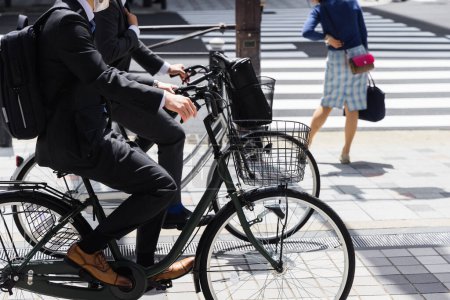 Téléchargez les photos : Photo de deux hommes d'affaires japonais à vélo sur le trottoir de Tokyo - en image libre de droit